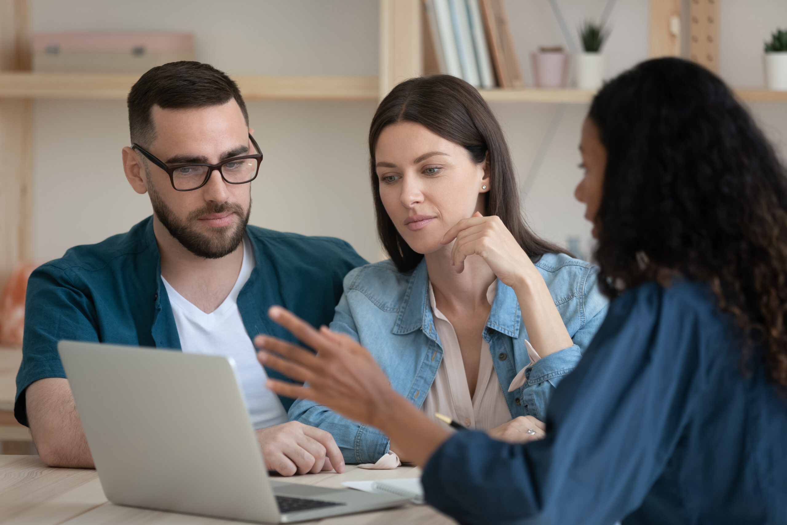 Focused young family couple listening to african american realtor at office